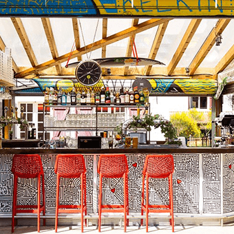 Bar coberto com banquetas vermelhas no JO&JOE Hossegor