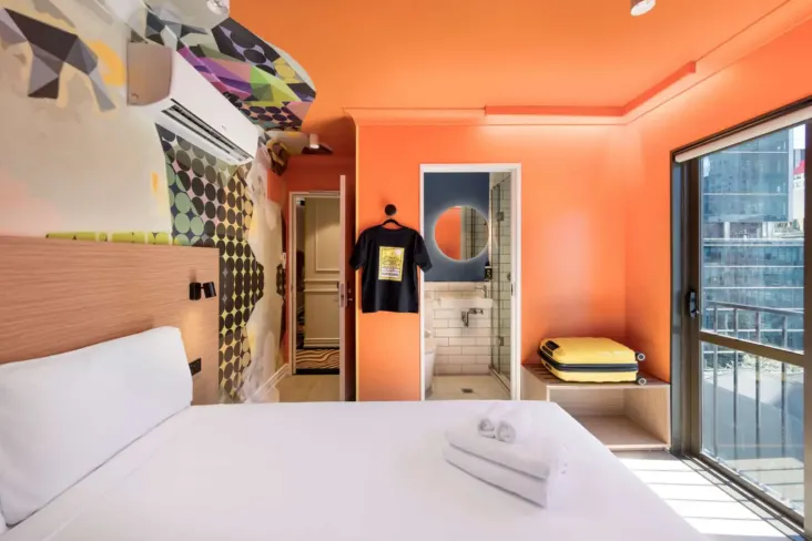 Chambre privée avec lit double et murs orange au JO&JOE Auckland