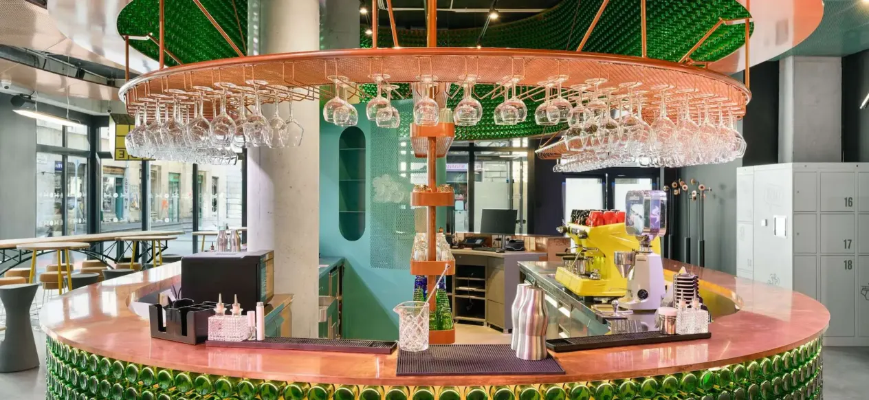 Comptoir de bar recouvert de bouteilles en verre vertes au JO&JOE Budapest