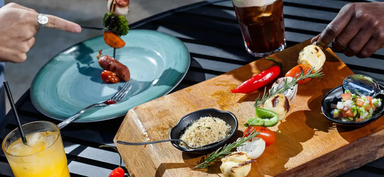 Brochettes, planche en bois garnie et boissons sur une table au JO&JOE Rio de Janeiro