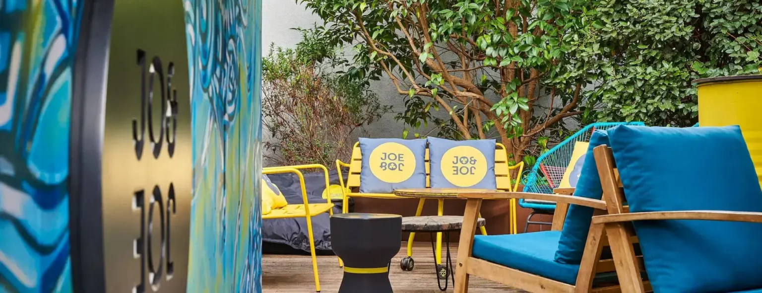 Terrasse jardin avec chaises à coussins bleus au JO&JOE Paris Nation
