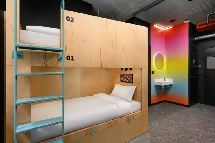 Dortoir avec lits superposés en bois, échelle et lavabo au JO&JOE Budapest