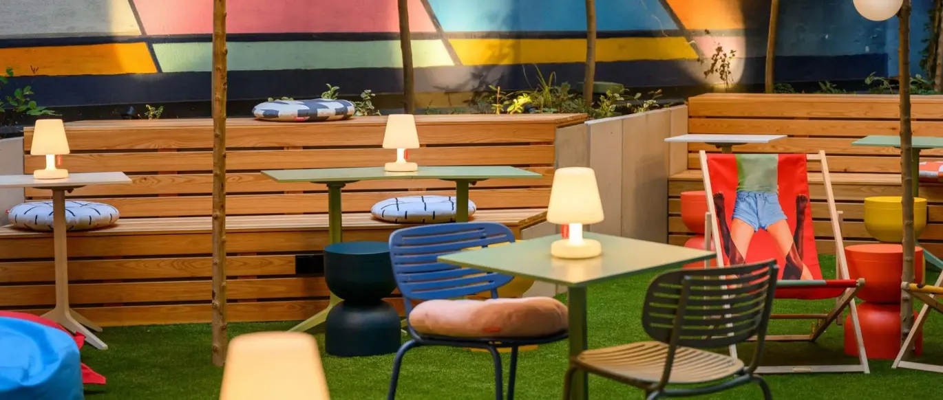Terrasse extérieure avec tables, lampes et fresque colorée au JO&JOE Budapest
