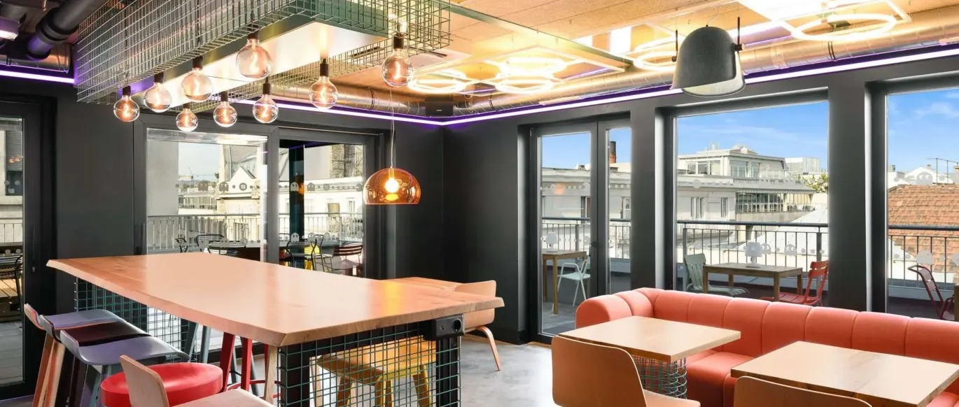 Salon avec table haute commune, tabourets et canapé au JO&JOE Budapest