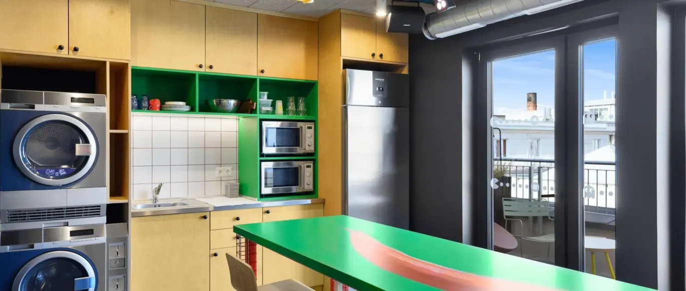 Espace cuisine avec machines à laver et table verte au JO&JOE Budapest