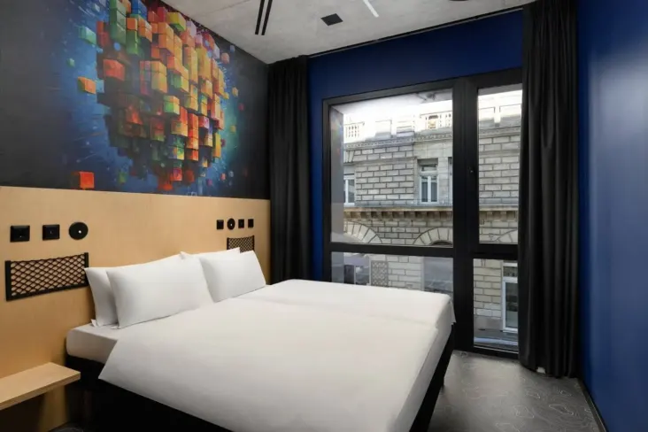 Lit double avec fresque colorée et fenêtre au JO&JOE Budapest