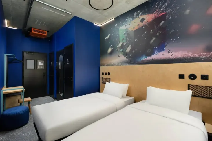 Chambre privée avec deux lits simples et une fresque murale au JO&JOE Budapest