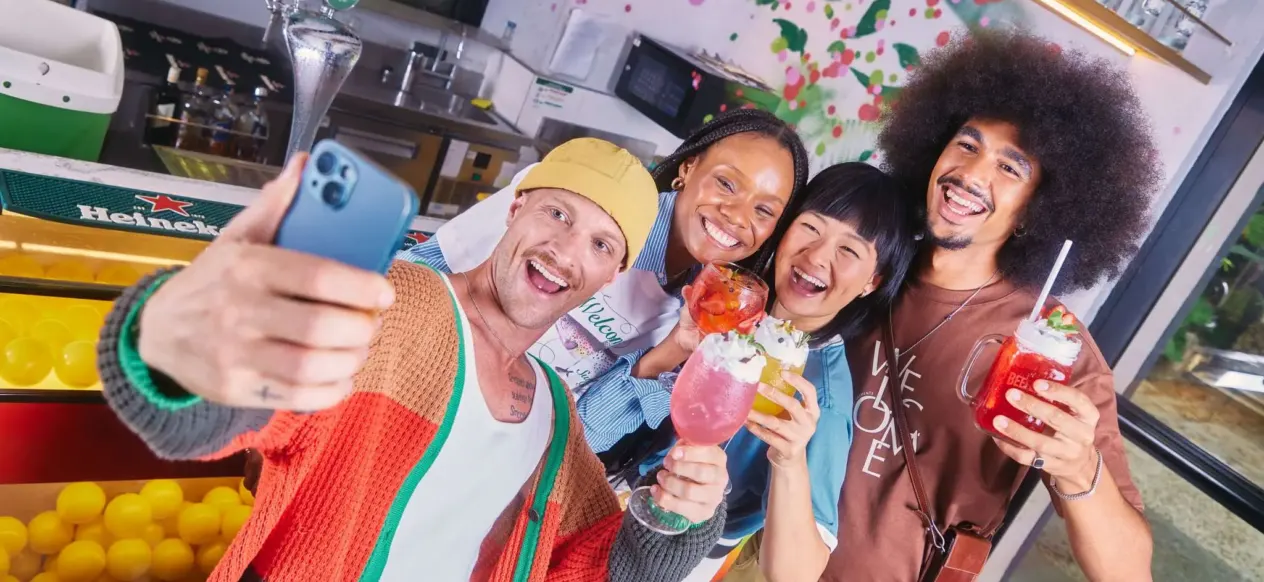 Grupo de pessoas com bebidas tirando uma selfie