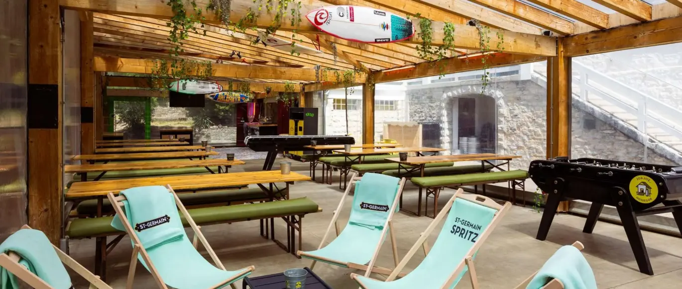 Terrasse couverte avec chaises longues et tables au JO&JOE Hossegor