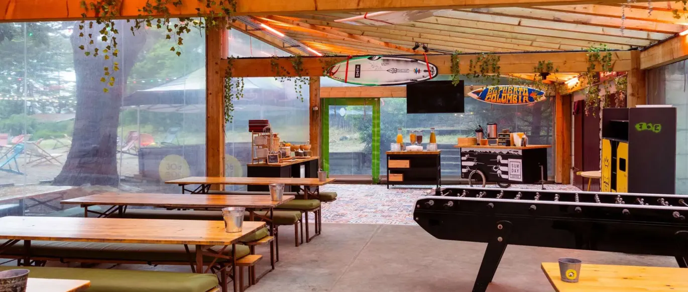 Terrasse couverte avec tables, transats et baby-foot au JO&JOE Hossegor