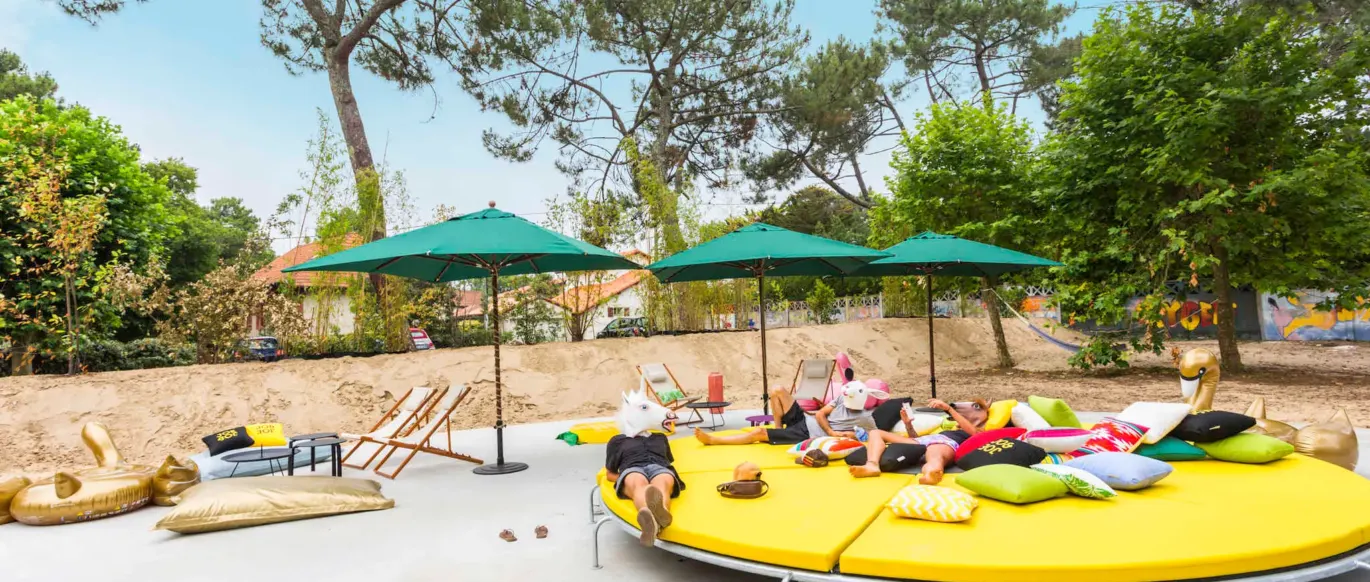Espace extérieur avec grand lit de repos rond et parasols au JO&JOE Hossegor