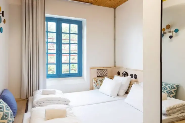 Chambre avec lit double, fenêtre bleue et planche de surf au JO&JOE Hossegor