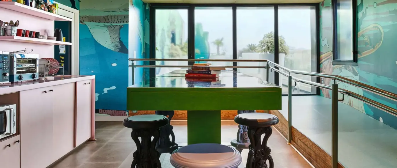 Cuisine commune avec table verte et tabourets au JO&JOE Paris Gentilly