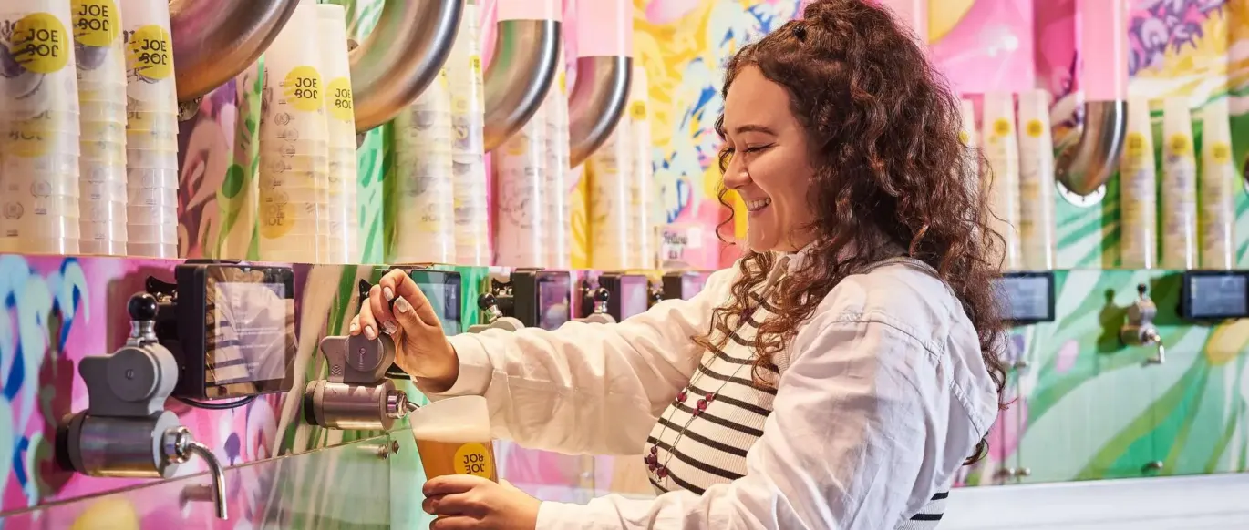 Personne se servant une boisson à un mur de tireuses en libre-service au JO&JOE Paris Gentilly