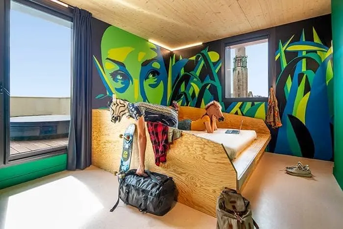 Chambre avec fresque verte, lit en bois et fenêtre au JO&JOE Paris Gentilly