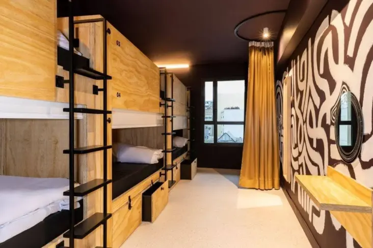 Dortoir avec lits superposés en bois et mur à motifs au JO&JOE Paris Nation