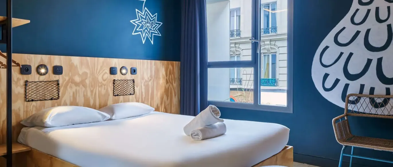 Chambre double avec lit en bois et fenêtre au JO&JOE Paris Nation