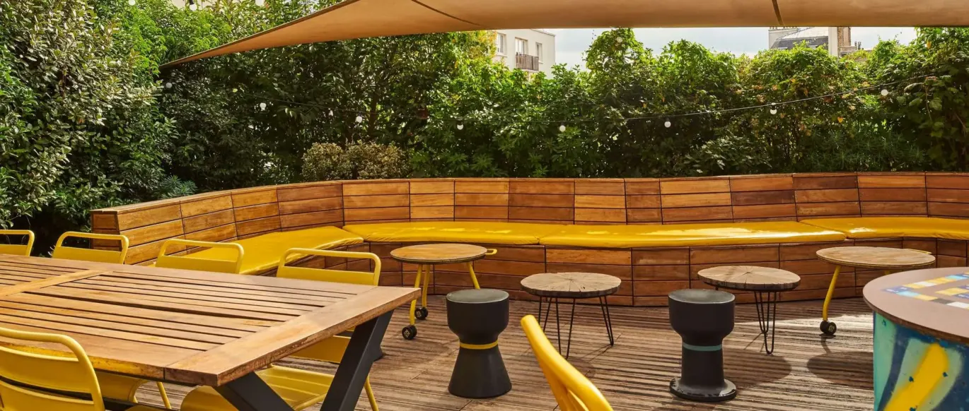 Terrasse avec chaises jaunes et banquettes en bois au JO&JOE Paris Nation