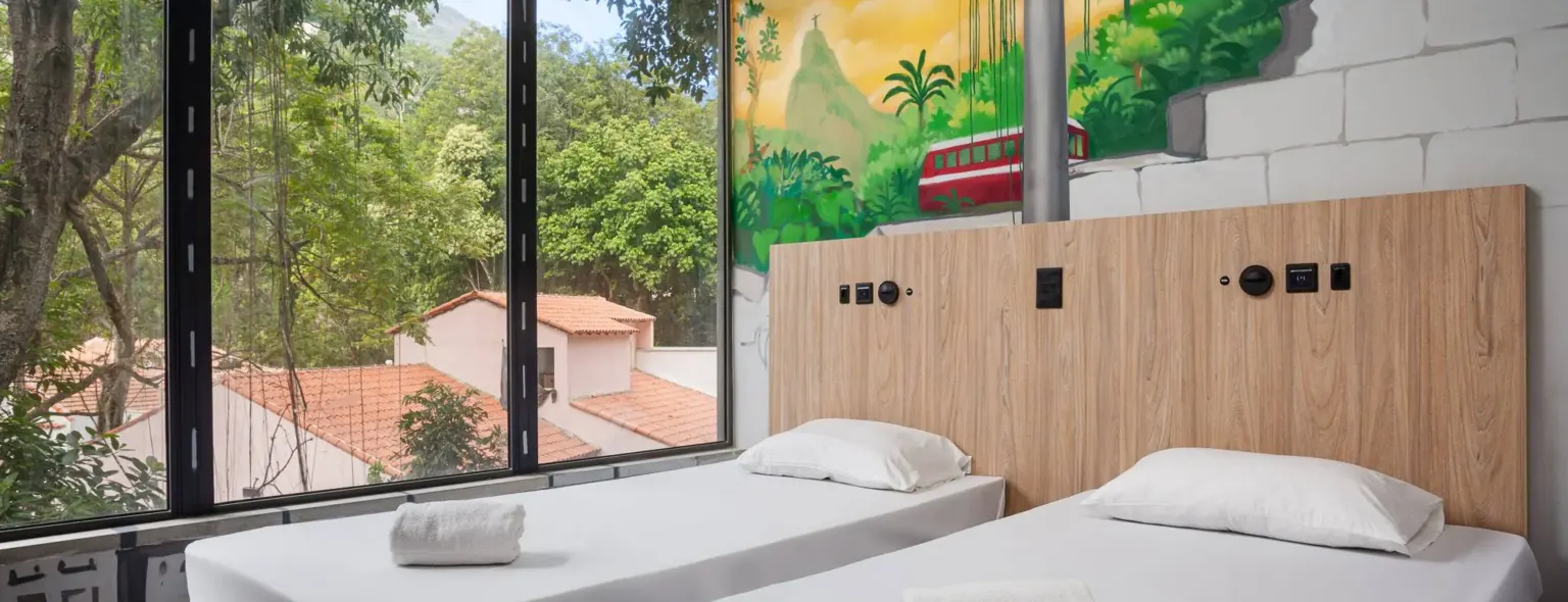 Chambre avec deux lits simples et fenêtre au JO&JOE Rio de Janeiro