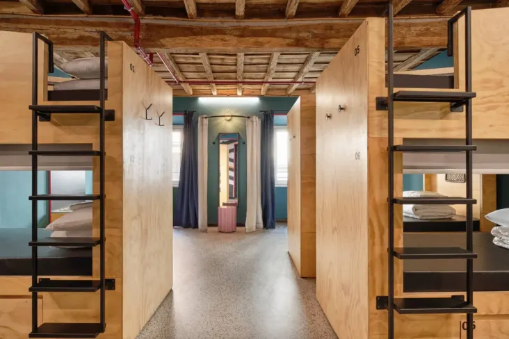 Dortoir avec lits superposés en bois et plafond à poutres au JO&JOE Rome