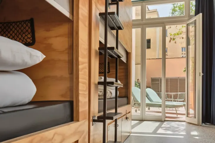 Dortoir avec lits superposés en bois et porte vers la terrasse au JO&JOE Rome