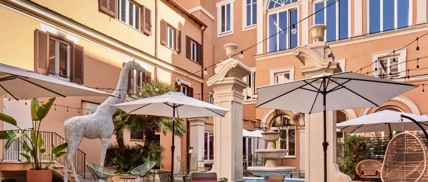 Cour avec tables, chaises et parasols au JO&JOE Rome