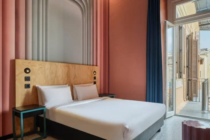 Chambre privée avec lit double et porte-fenêtre donnant sur un balcon au JO&JOE Rome