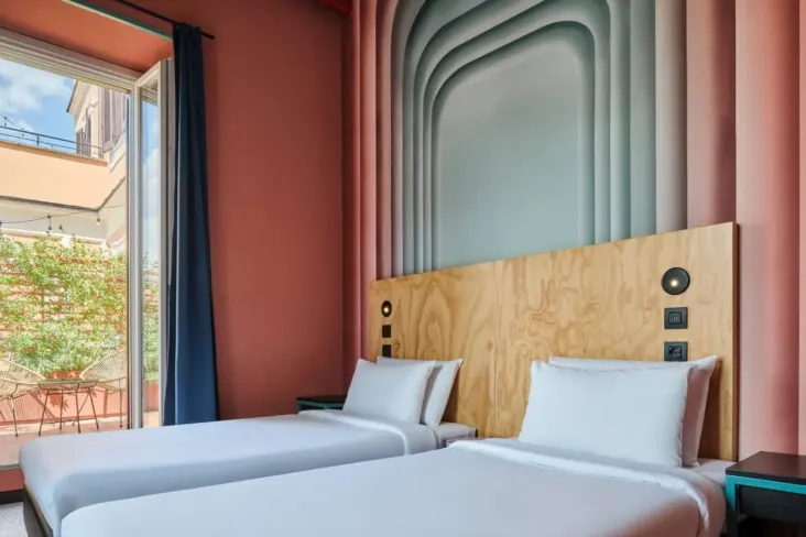 Chambre à deux lits avec tête de lit en bois et balcon au JO&JOE Rome