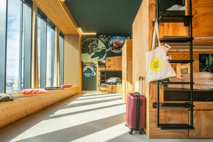 Dortoir avec lits superposés en bois et banquette près de la fenêtre au JO&JOE Vienne