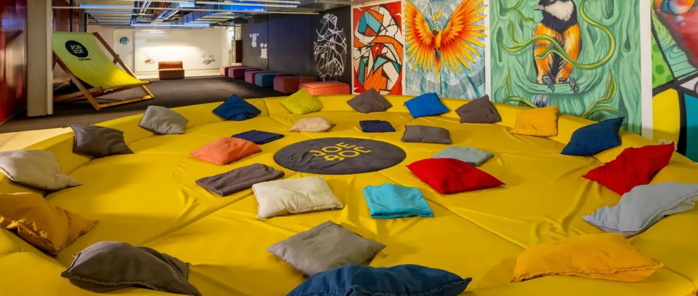 Espace commun avec grande banquette ronde jaune et fresques au JO&JOE Vienne