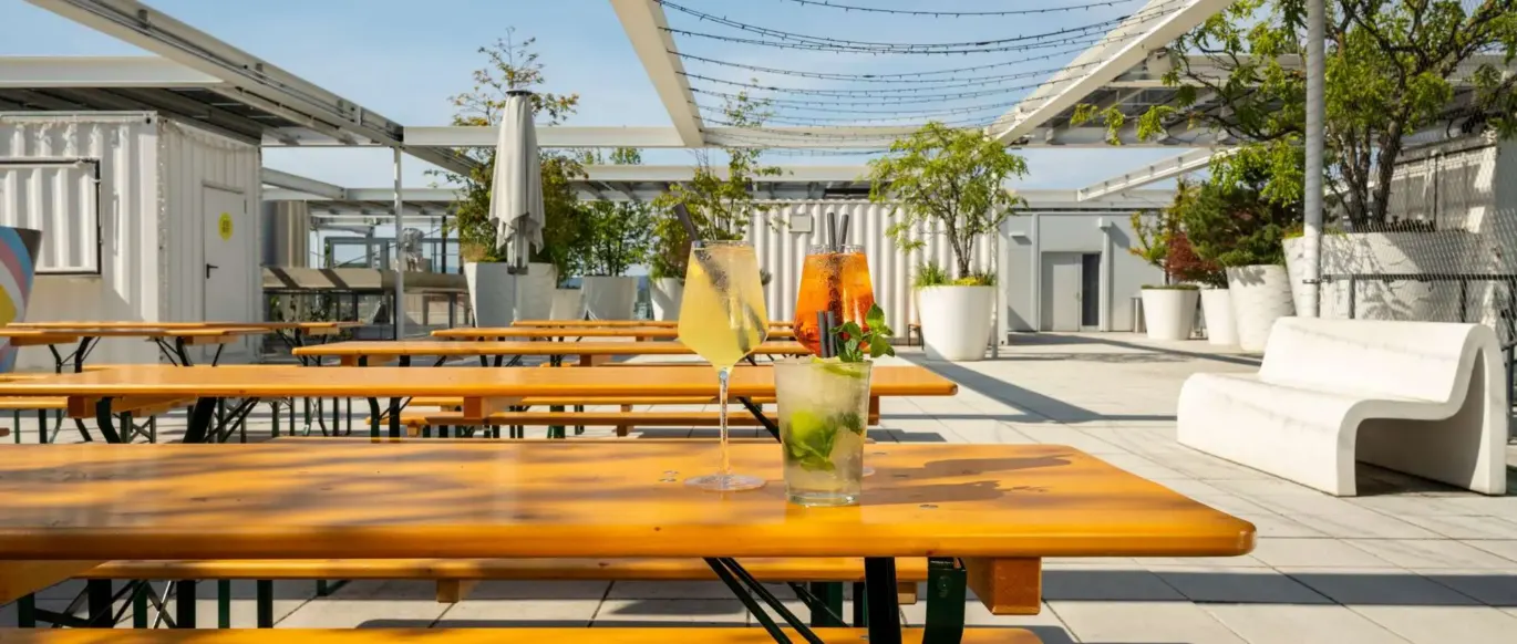 Terrasse sur le toit avec tables et bancs en bois au JO&JOE Vienne