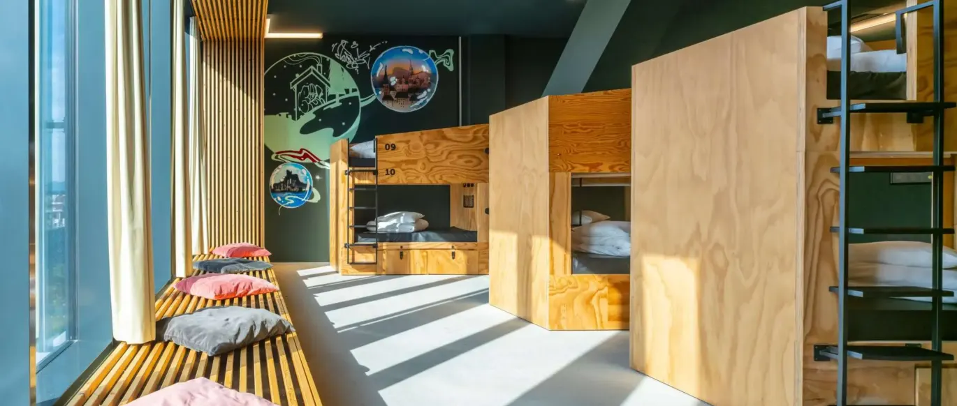 Dortoir avec lits superposés en bois et banquette près de la fenêtre au JO&JOE Vienne